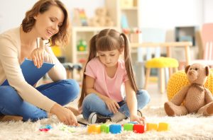 woman sitting with a young girl and her toys