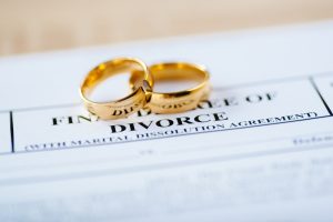 two wedding bands on top of divorce paperwork