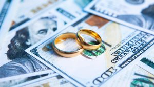 two wedding bands on top of hundred dollar bills