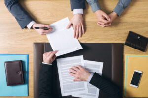 man and woman sitting at the lawyers's desk and signing important documents