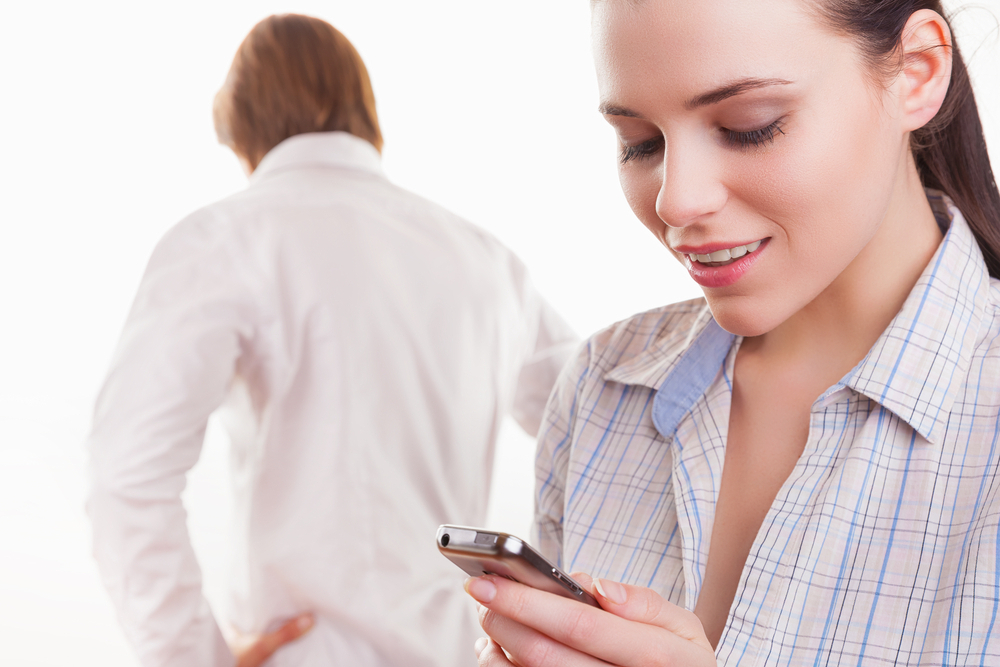 woman looking with a smile on your phone in the foreground